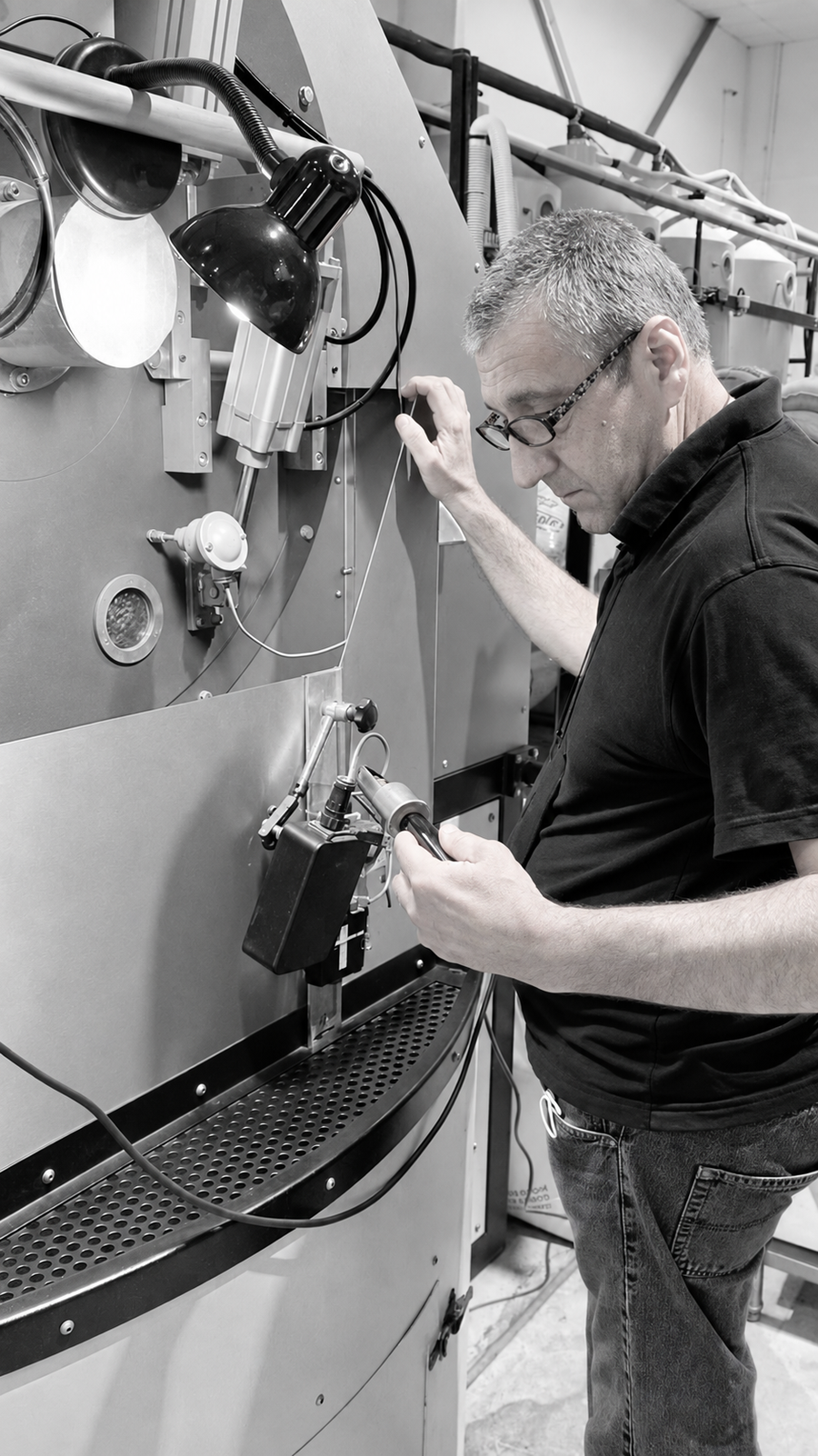 Mood Espressoβs roast master checking coffee at the roasting equipment